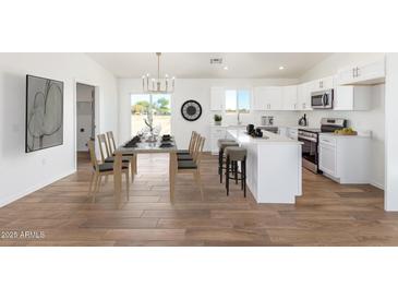 Bright, open kitchen with white cabinets, stainless steel appliances, and a dining area perfect for entertaining at 5055 N Jayson Rd, Casa Grande, AZ 85194