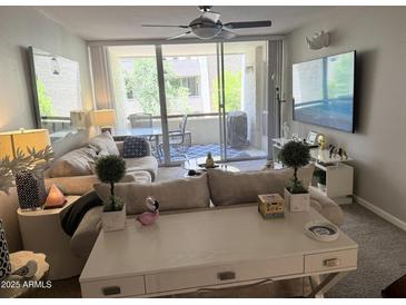 Cozy living room featuring a couch, TV, and a sliding glass door to a balcony at 7625 E Camelback Rd # B241, Scottsdale, AZ 85251