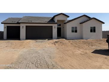 New construction featuring a three-car garage, desert landscaping, and a modern stucco facade at 9429 W Sandstone Mountain Dr, Casa Grande, AZ 85194