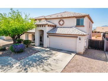 Inviting two-story home featuring a well-manicured front yard, charming architectural details, and an attached two-car garage at 9735 W Kirby Ave, Tolleson, AZ 85353