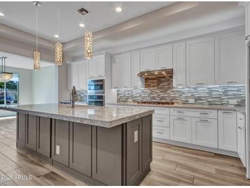 Modern kitchen features a large island, stainless steel appliances, white cabinets, and stylish lighting at 16881 W Merrell St, Goodyear, AZ 85395