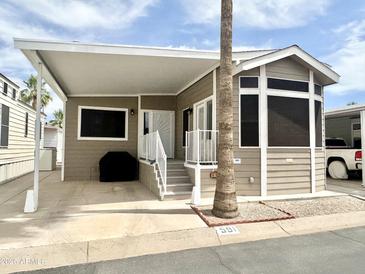 Charming manufactured home with covered parking, desert landscaping, and a welcoming front porch entry at 591 S Ironstone Dr, Apache Junction, AZ 85119