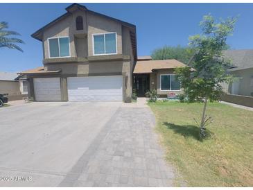 Charming two-story home with a three-car garage, a walkway, and a well-manicured lawn at 8742 W Edgemont Ave, Phoenix, AZ 85037