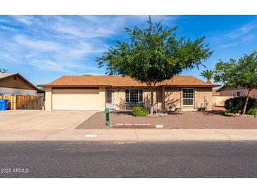 Charming single-story home featuring a well-maintained front yard, mature tree, and a two-car garage at 12241 N 49Th Ave, Glendale, AZ 85304