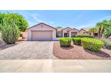 Charming single-story home with manicured landscaping, a two-car garage and a brick-paved driveway at 20215 N Mariposa Way, Surprise, AZ 85374