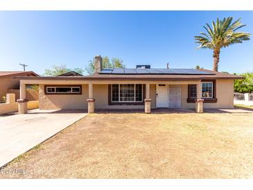 Inviting single-story home with a desert landscape, solar panels, and a mature palm tree at 2064 W 2Nd St, Mesa, AZ 85201