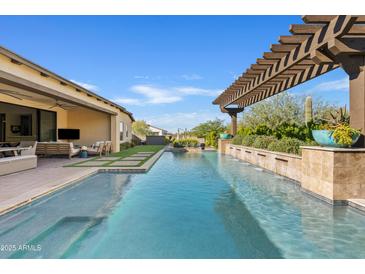 Inviting backyard pool with pergola, water feature, and lush desert landscaping for relaxation and outdoor enjoyment at 5420 E Duane Ln, Cave Creek, AZ 85331