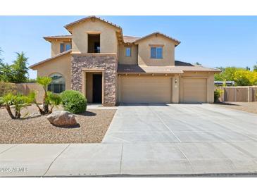 Two-story home with a three-car garage, stone accents, and manicured landscaping at 11048 E Quintana Ave, Mesa, AZ 85212