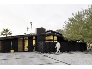 Striking modern home with sleek, dark exterior, complemented by desert landscaping and a minimalist design at 4032 N 45Th Pl, Phoenix, AZ 85018