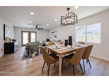 Staged dining room boasts modern light fixture, wood floors, and stylish seating, flowing into the spacious living room at 4234 E Winnetka Dr, Phoenix, AZ 85044