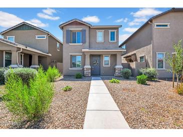 Charming two-story home featuring neutral paint, desert landscaping, and inviting front porch entry at 5741 W Warner St, Phoenix, AZ 85043