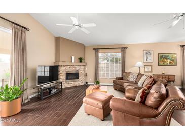 Cozy living room with a stone fireplace, leather furniture, and large window at 11807 E Clinton St, Scottsdale, AZ 85259