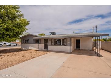 Inviting single-story home features a low-maintenance desert landscape, covered parking, and a charming white brick facade at 1654 E 2Nd St, Mesa, AZ 85203
