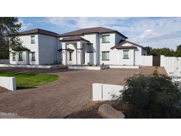 Elegant, two-story home with a well-manicured lawn, brick driveway, and pristine white exterior finish at 2060 E Quartz St, Mesa, AZ 85213