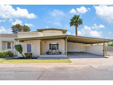 Charming single-level home with a covered carport, landscaped yard, and a sunny yellow door at 6001 N 10Th Way, Phoenix, AZ 85014