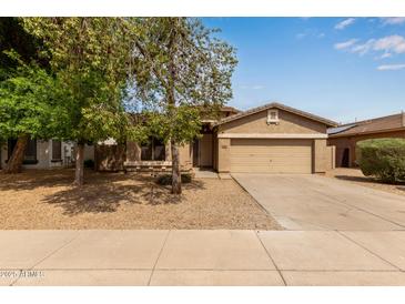 Charming single-story home with a two car garage, desert landscaping, and mature shade trees at 2590 S Buckaroo Trl, Gilbert, AZ 85295