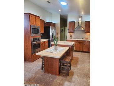 A kitchen with stainless steel appliances, brown cabinets, a kitchen island, and neutral tile flooring at 9302 E Broadway Rd # 157, Mesa, AZ 85208
