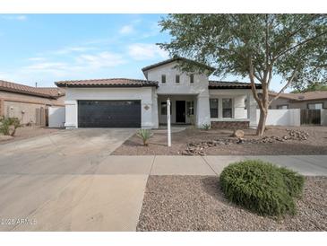 Charming single-story home with a well-manicured front yard and a black two car garage door at 20823 S 185Th Way, Queen Creek, AZ 85142