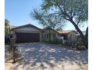 Charming single-story brick home featuring a two-car garage, desert landscaping, and a well-maintained front yard at 402 E Claremont St, Phoenix, AZ 85012