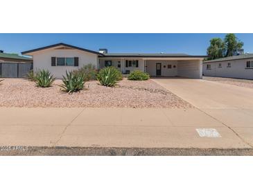 Charming single-story home featuring desert landscaping, a carport, and fresh, white paint in a well-maintained neighborhood at 701 N 55Th Pl, Mesa, AZ 85205
