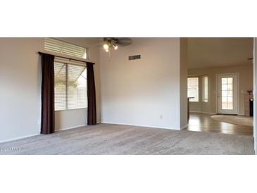 Bright living room featuring neutral carpet, ceiling fan and natural light from large windows at 7825 W Crocus Dr, Peoria, AZ 85381