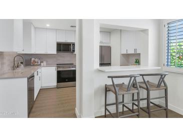 Modern kitchen with stainless steel appliances and white cabinets with bar stool seating at 4201 E Camelback Rd # 70, Phoenix, AZ 85018