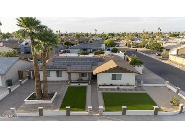 Charming home featuring a well-manicured lawn, solar panels, and elegant desert landscaping at 4202 W Purdue Ave, Phoenix, AZ 85051