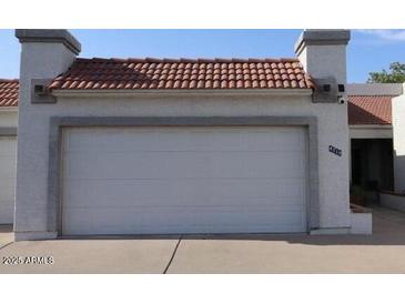 Attached two-car garage featuring a red tile roof and a white door at 4718 W Sanna St, Glendale, AZ 85302