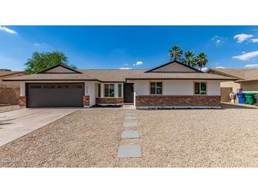 Charming single-story home with desert landscaping, complemented by a two car garage and palm trees at 2348 E Diamond Ave, Mesa, AZ 85204