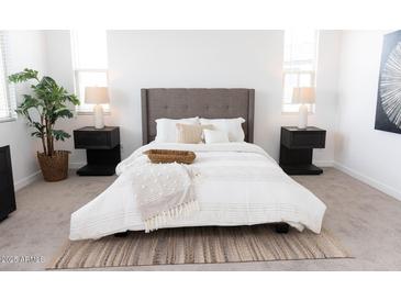 Beautifully staged bedroom featuring a plush bed, neutral tones, and ample natural light from two bright windows at 5928 S Daisy Patch Pl, Phoenix, AZ 85040