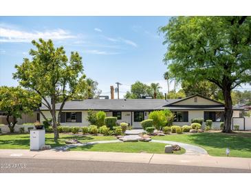 Charming single-story home with lush landscaping, mature trees, and a stone walkway leading to the entrance at 7508 N 13Th Ave, Phoenix, AZ 85021