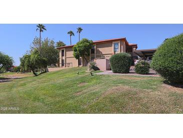 Inviting condo with lush green lawn and mature palm trees set against a clear blue sky at 10410 N Cave Creek Rd # 2220, Phoenix, AZ 85020