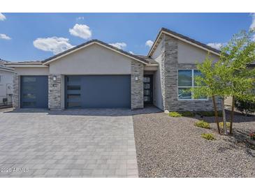 Beautiful single-Gathering home featuring stone accents, paver driveway, and a modern garage door at 10509 W Harmony Ln, Peoria, AZ 85382