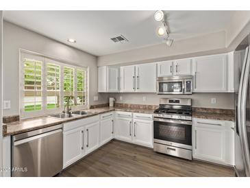 Well-lit kitchen with stainless steel appliances and white cabinetry offers a modern and clean aesthetic at 2438 W Via Dona Rd, Phoenix, AZ 85085