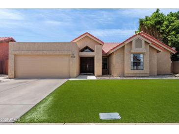 Charming single-story home with lush green lawn, desert landscaping, and a red tile roof at 11131 E Becker Ln, Scottsdale, AZ 85259