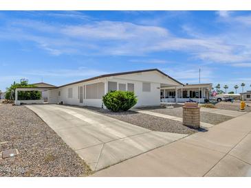 Charming single-story home features a white exterior, low maintenance landscaping, and covered carport at 2241 N Nicklaus Dr, Mesa, AZ 85215