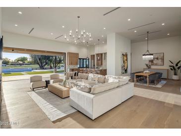 Bright open-concept living space features a modern chandelier, light wood floors, and seamless indoor-outdoor living at 23002 N Country Club Trl, Scottsdale, AZ 85255