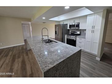 Bright kitchen with granite counters, stainless appliances, and a skylight for natural light at 3849 W Mauna Loa Ln, Phoenix, AZ 85053