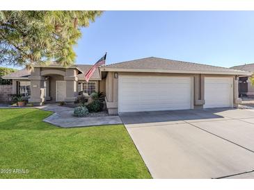 Charming single-story home with a three-car garage, well-maintained lawn, and an American flag at 4407 W Avenida Del Sol --, Glendale, AZ 85310