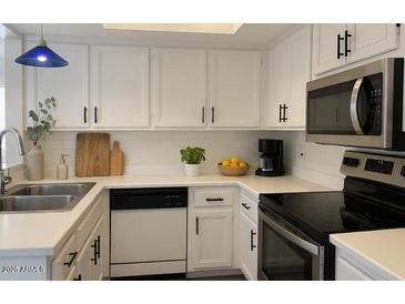 Bright kitchen features white cabinetry, stainless steel appliances, and ample counter space at 461 W Holmes Ave # 271, Mesa, AZ 85210