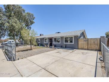 Charming single-story home featuring a gray exterior, spacious driveway, and secure fenced front yard at 7135 W Flower St, Phoenix, AZ 85033