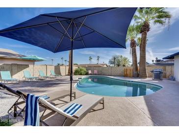 Inviting backyard pool area featuring lounge chairs, shade umbrella, and lush palm trees perfect for relaxation at 1142 E Westchester Dr, Tempe, AZ 85283
