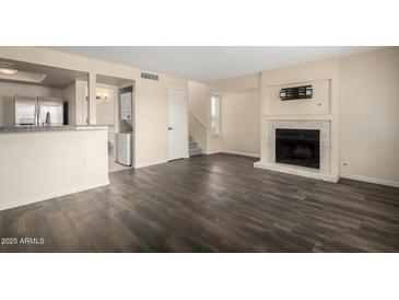 Spacious living room with dark wood floors, a fireplace, and stainless steel appliances at 1645 W Baseline Rd # 2098, Mesa, AZ 85202