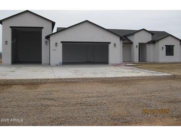 Modern home featuring multiple garage spaces and a white stucco facade with black trim at 34449 N Elk Run Rd, San Tan Valley, AZ 85143