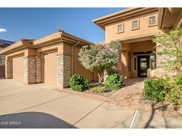 Beautiful home exterior with a well-manicured front yard, desert landscaping, and a three-car garage at 42023 N Bridlewood Way, Anthem, AZ 85086