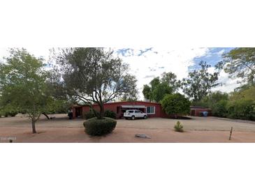 Charming single-story home featuring a red facade, a private driveway, and lush greenery at 12402 N 65Th St, Scottsdale, AZ 85254