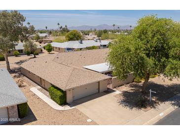 A high angle view of the exterior showing the roof, two-car garage, and nearby trees and community at 12831 W Maplewood Dr, Sun City West, AZ 85375