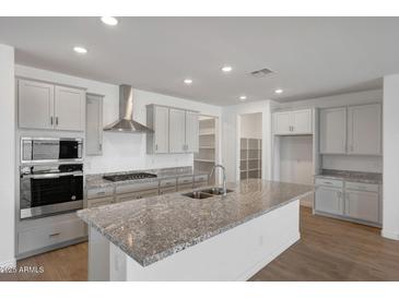 This kitchen features stainless steel appliances, granite countertops, and gray cabinetry at 14789 W Lariat Ln, Surprise, AZ 85387