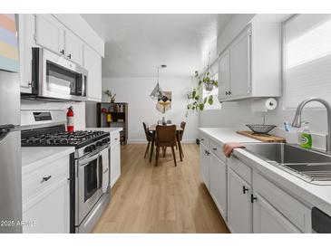 Bright kitchen features white cabinets, stainless steel appliances, and a view of the dining area at 1111 E Turney Ave # 3, Phoenix, AZ 85014