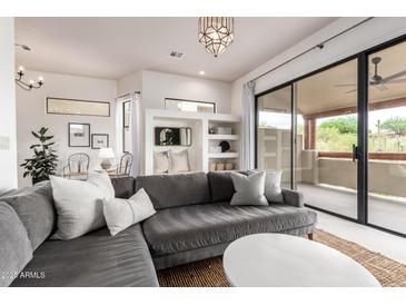 Bright living room with a gray sofa, white pillows, and a large window view to the patio at 12642 N Mountainside Dr # B, Fountain Hills, AZ 85268